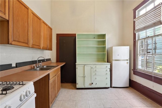 271214 Burgundy St, New Orleans, LA 70117 - kitchen with white appliances, healthy amount of natural light, light tile patterned flooring, brown cabinetry, and a towering ceiling