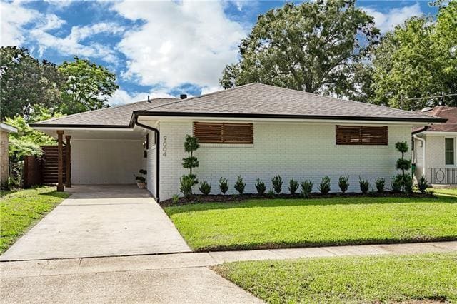9004 Camille Ct, River Ridge, LA 70123 - ranch-style house featuring concrete driveway, a front lawn, brick siding, an attached carport, and roof with shingles