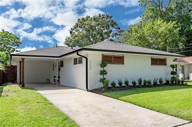 9004 Camille Ct, River Ridge, LA 70123 - view of front of house featuring driveway, a front lawn, an attached carport, brick siding, and roof with shingles