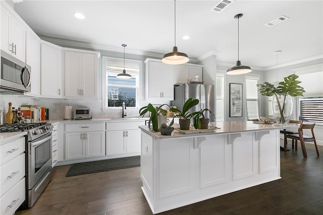 1641 Continental Dr, Covington, LA 70433 - kitchen featuring appliances with stainless steel finishes, a sink, an island with sink, light countertops, and crown molding