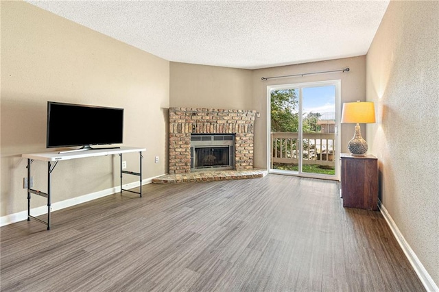736 Village Rd Unit A, Kenner, LA 70065 - unfurnished living room with wood finished floors, a textured ceiling, a fireplace, baseboards, and a textured wall