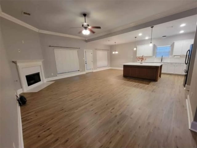 40153 Maison Lafitte Blvd, Ponchatoula, LA 70454 - living area with light wood-type flooring, a ceiling fan, a fireplace with flush hearth, recessed lighting, and ornamental molding