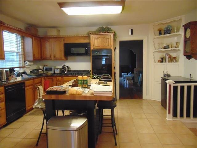 3008 Beaulieu St, Metairie, LA 70001 - kitchen with black appliances, light tile patterned floors, dark countertops, and brown cabinetry