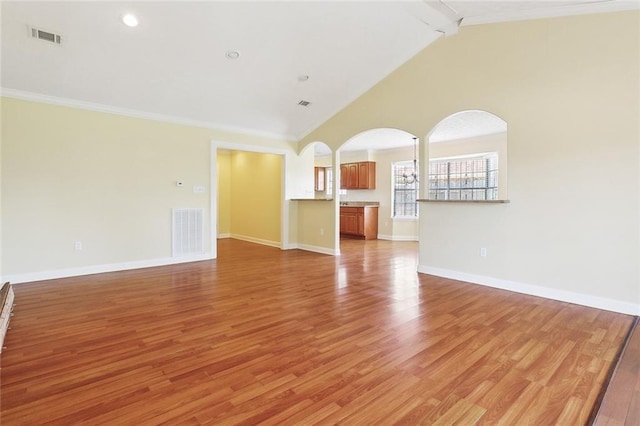 5736 E Louis Prima Dr, New Orleans, LA 70128 - unfurnished living room with arched walkways, beamed ceiling, light wood-style flooring, baseboards, and ornamental molding