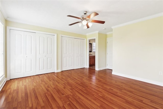 5736 E Louis Prima Dr, New Orleans, LA 70128 - unfurnished bedroom featuring wood finished floors, multiple closets, ornamental molding, baseboards, and a ceiling fan