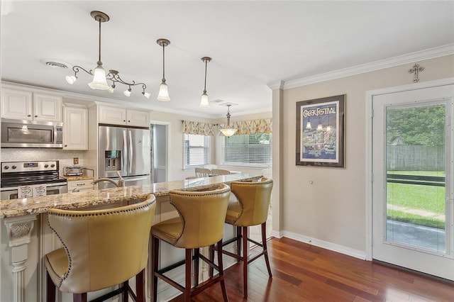 1417 Washington Ct, Slidell, LA 70458 - kitchen featuring stainless steel appliances, a kitchen bar, dark wood-type flooring, ornamental molding, and light stone counters