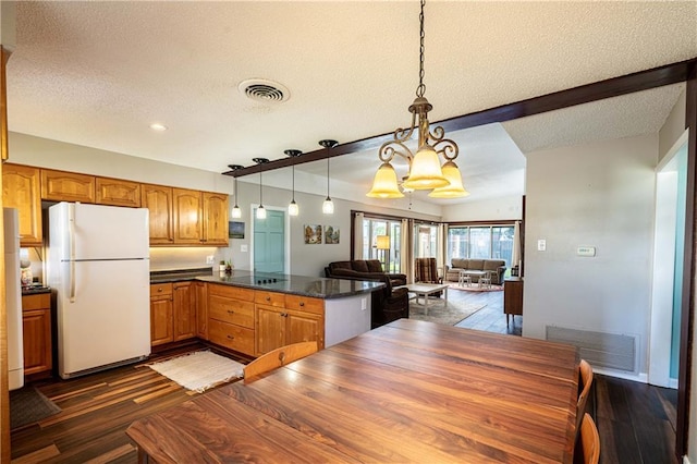 4401 Apollo Dr, Metairie, LA 70003 - kitchen featuring freestanding refrigerator, a textured ceiling, dark wood-type flooring, dark countertops, and a peninsula