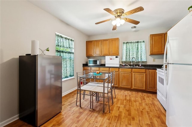 3113 Terrace Ave, Slidell, LA 70458 - kitchen featuring white appliances, a sink, dark countertops, light wood finished floors, and brown cabinetry