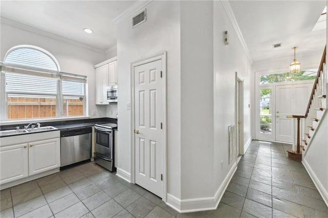 506 Papworth Ave, Metairie, LA 70005 - kitchen featuring stainless steel appliances, ornamental molding, a sink, baseboards, and white cabinetry