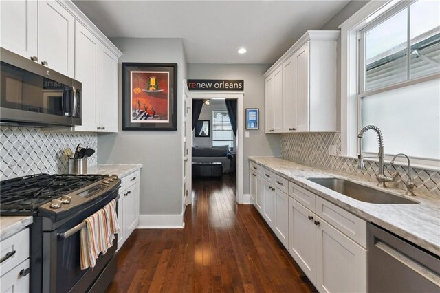 2728 Bienville St, New Orleans, LA 70119 - kitchen with appliances with stainless steel finishes, a sink, baseboards, white cabinetry, and recessed lighting