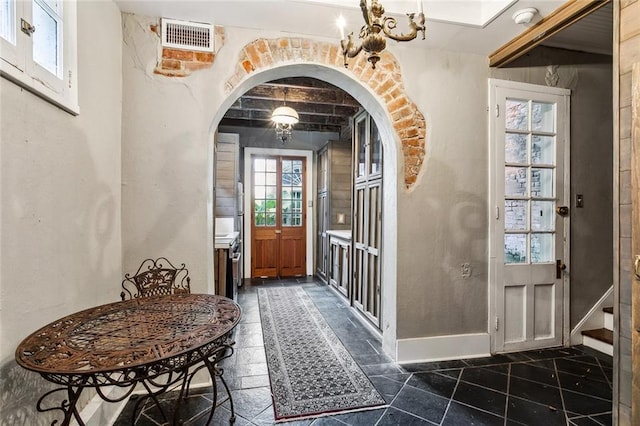 826 Bourbon St Unit B, New Orleans, LA 70116 - foyer with arched walkways, a chandelier, and dark tile patterned flooring