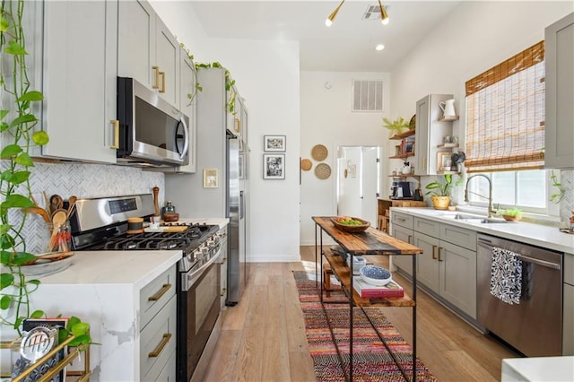 2712 Saint Thomas St, New Orleans, LA 70130 - kitchen with appliances with stainless steel finishes, a sink, gray cabinets, decorative backsplash, and light wood finished floors