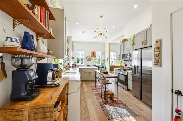 2712 Saint Thomas St, New Orleans, LA 70130 - kitchen with stainless steel appliances, a sink, open shelves, a chandelier, and gray cabinetry