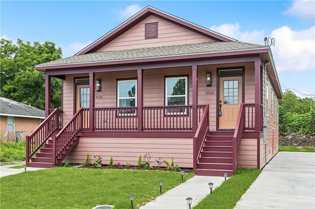 313331 Clouet St, New Orleans, LA 70126 - view of front facade with a porch, a shingled roof, a front yard, and stairway