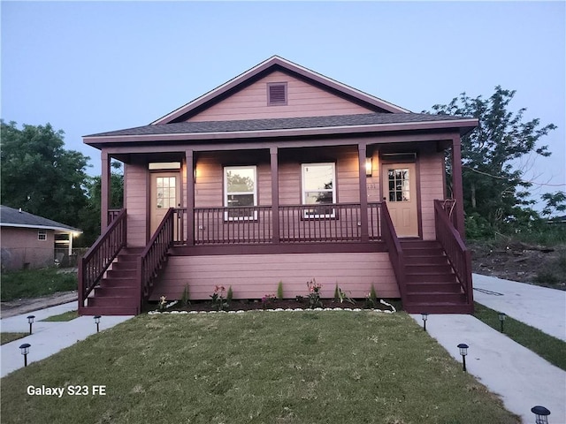313331 Clouet St, New Orleans, LA 70126 - view of front of property featuring stairway, a porch, a shingled roof, and a front lawn