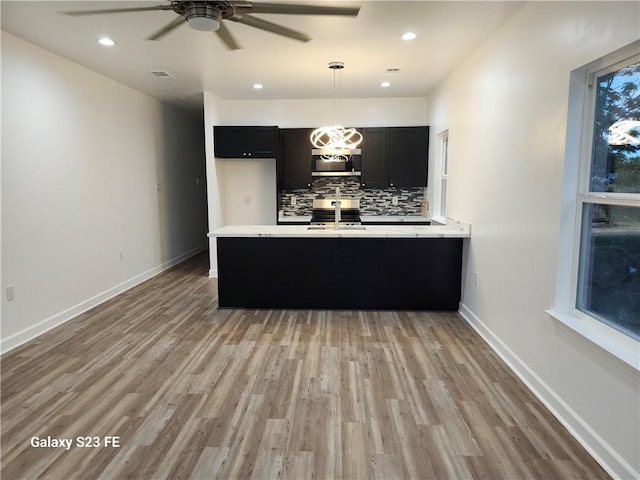 313331 Clouet St, New Orleans, LA 70126 - kitchen featuring dark cabinetry, ceiling fan, decorative backsplash, light countertops, and light wood-type flooring