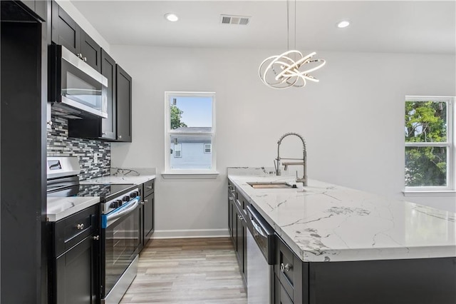 313331 Clouet St, New Orleans, LA 70126 - kitchen with stainless steel appliances, dark cabinetry, a peninsula, healthy amount of natural light, and recessed lighting