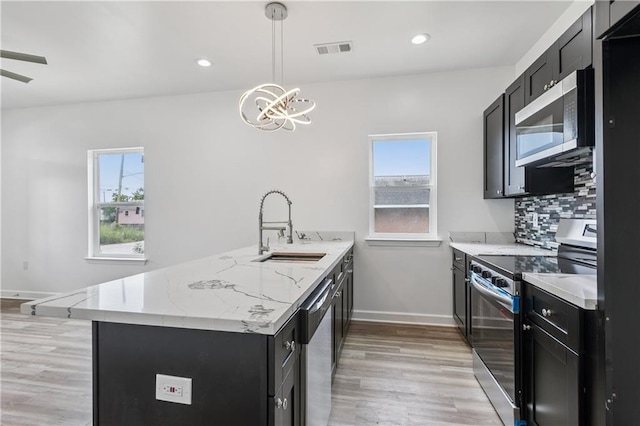 313331 Clouet St, New Orleans, LA 70126 - kitchen with stainless steel appliances, a sink, dark cabinetry, a peninsula, and healthy amount of natural light