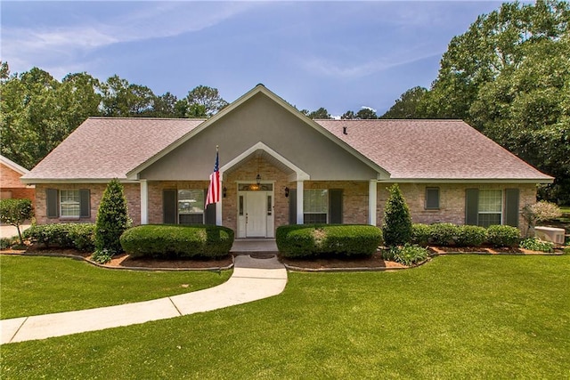 ranch-style home featuring a front yard, roof with shingles, and brick siding