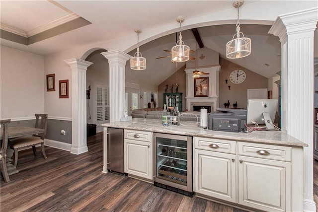 bar area with beverage cooler, decorative columns, a ceiling fan, dark wood finished floors, and arched walkways