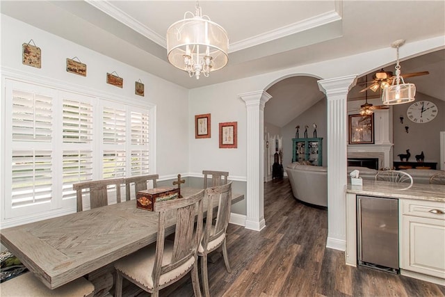 dining space featuring decorative columns, beverage cooler, a ceiling fan, dark wood-type flooring, and arched walkways