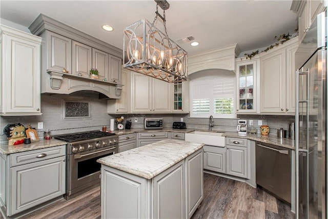 kitchen featuring high quality appliances, a sink, a chandelier, decorative backsplash, and glass insert cabinets