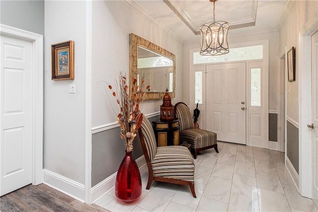 foyer with baseboards, a chandelier, ornamental molding, light marble finish floors, and a tray ceiling