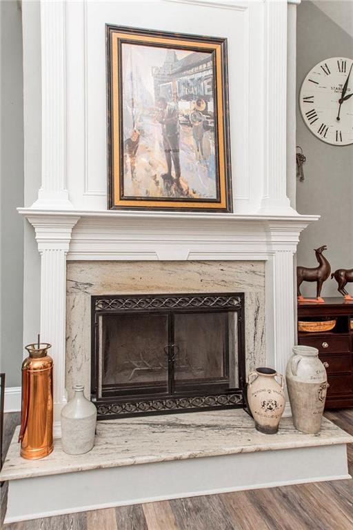 detailed view of a high end fireplace, wood finished floors, and decorative columns
