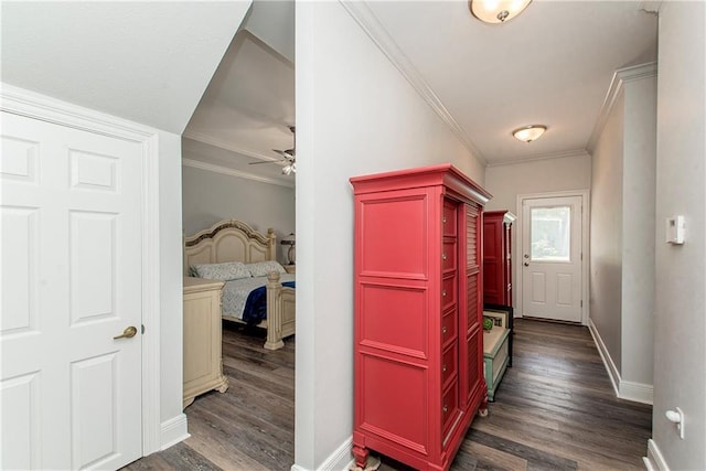 hall featuring dark wood finished floors, crown molding, and baseboards