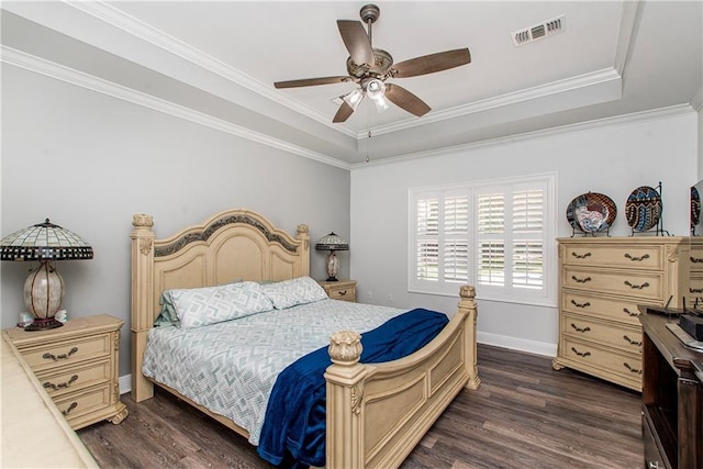 bedroom featuring dark wood-type flooring, ornamental molding, a ceiling fan, baseboards, and a tray ceiling