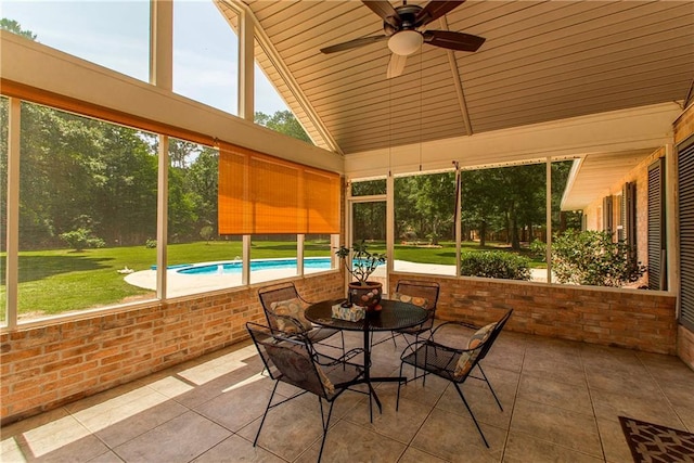 sunroom featuring ceiling fan, outdoor dining space, and vaulted ceiling