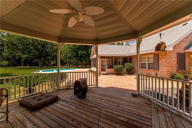 wooden terrace featuring ceiling fan, a sunroom, a yard, an outdoor pool, and view of scattered trees