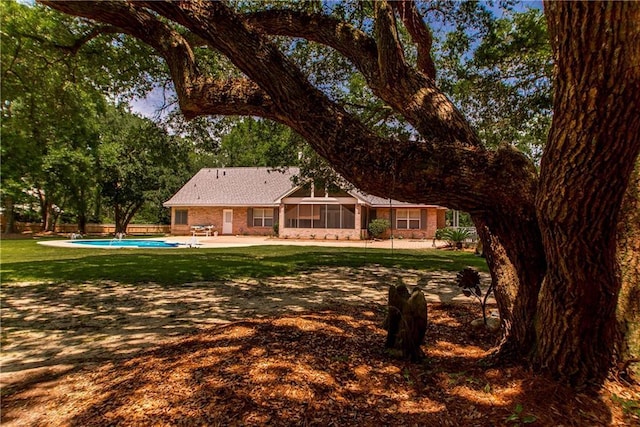 back of house featuring an outdoor pool, a patio area, brick siding, and a lawn