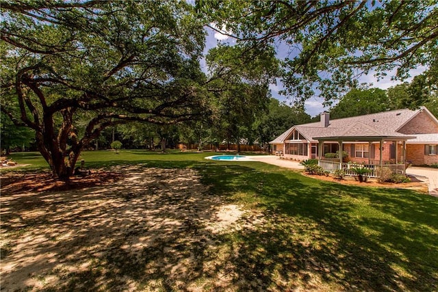 view of yard featuring an outdoor pool, a patio, and view of wooded area