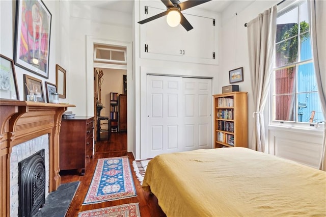 2329 Dauphine St, New Orleans, LA 70117 - bedroom featuring dark wood-type flooring, a closet, a fireplace with flush hearth, and a ceiling fan