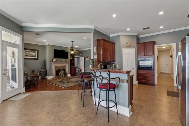 11446 Copperwood Dr, Denham Springs, LA 70726 - kitchen with oven, freestanding refrigerator, light tile patterned floors, a kitchen breakfast bar, and recessed lighting