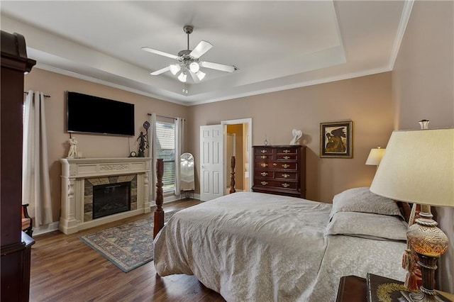 11446 Copperwood Dr, Denham Springs, LA 70726 - bedroom with a tray ceiling, wood finished floors, a glass covered fireplace, a ceiling fan, and ornamental molding