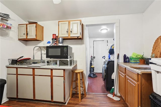 3979 S Front St, New Orleans, LA 70115 - kitchen with independent washer and dryer, black microwave, dark wood-style floors, light countertops, and a sink