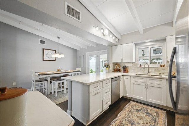 33 Caribou Ct, Metairie, LA 70003 - kitchen featuring appliances with stainless steel finishes, a sink, a peninsula, tasteful backsplash, and light countertops