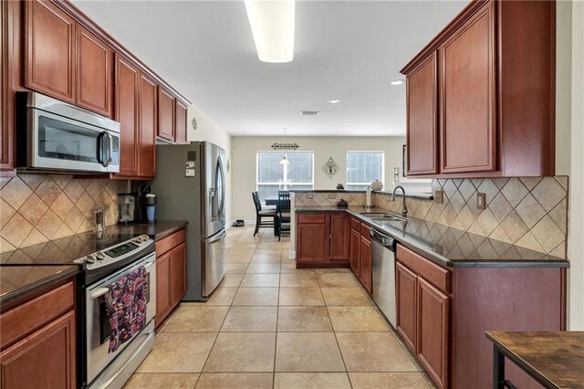 682 Amy Ct, Covington, LA 70433 - kitchen with appliances with stainless steel finishes, dark countertops, a sink, backsplash, and light tile patterned flooring