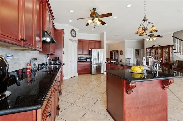 1681 Vela Cv, Slidell, LA 70458 - kitchen featuring stainless steel appliances, a ceiling fan, reddish brown cabinets, under cabinet range hood, and ornamental molding