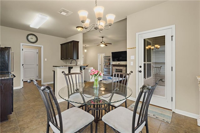 20413 Palm Blvd, Covington, LA 70435 - dining area featuring a chandelier, a ceiling fan, baseboards, a stone fireplace, and tile patterned floors