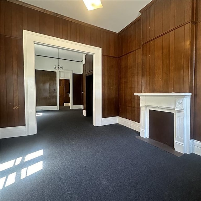 937-939 N Claiborne Ave, New Orleans, LA 70116 - unfurnished living room featuring dark colored carpet, wood walls, a fireplace with flush hearth, baseboards, and a chandelier