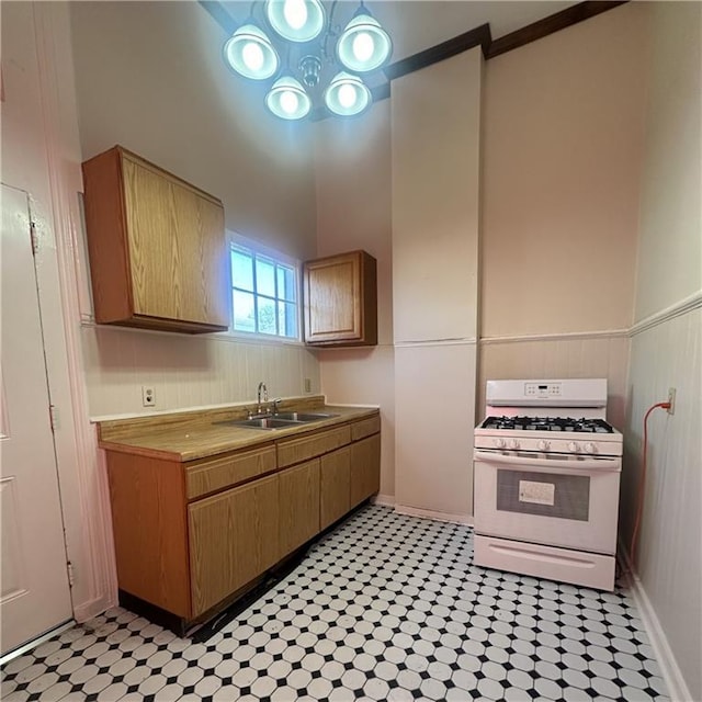 937-939 N Claiborne Ave, New Orleans, LA 70116 - kitchen with white range with gas stovetop, a sink, a towering ceiling, light countertops, and light floors