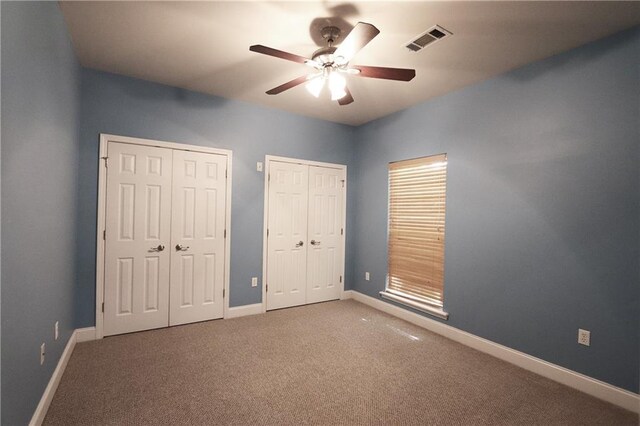 47013 Rivergate Dr, Robert, LA 70455 - unfurnished bedroom featuring multiple closets, carpet flooring, baseboards, and a ceiling fan