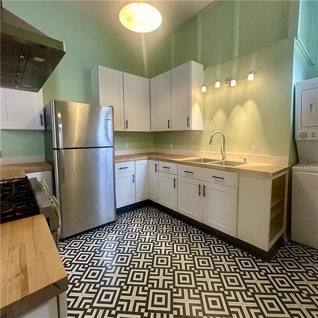 1915-1917 Bayou Rd, New Orleans, LA 70116 - kitchen with freestanding refrigerator, stacked washing machine and dryer, ventilation hood, a sink, and dark flooring