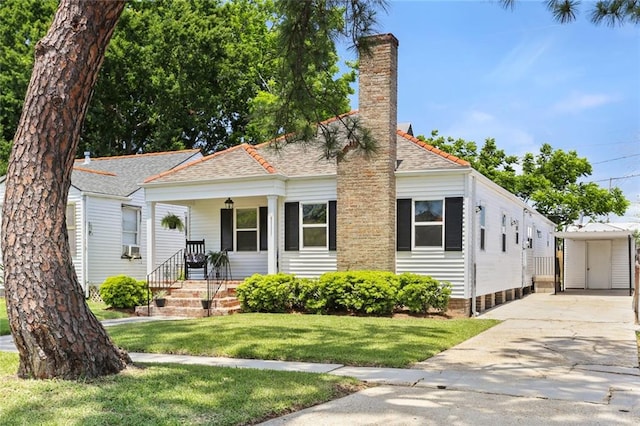 18 Davis Blvd, Jefferson, LA 70121 - view of front facade featuring a front yard, concrete driveway, a chimney, covered porch, and roof with shingles