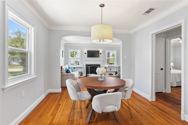 18 Davis Blvd, Jefferson, LA 70121 - dining space with arched walkways, light wood-style floors, a fireplace, and crown molding