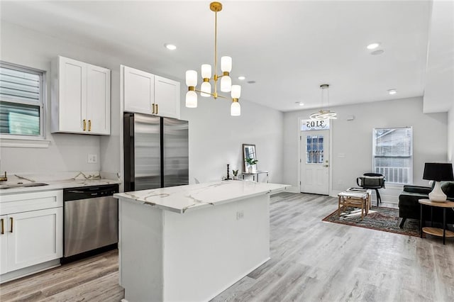 310507 Toulouse St, New Orleans, LA 70119 - kitchen with stainless steel appliances, white cabinets, light stone countertops, light wood-style flooring, and recessed lighting