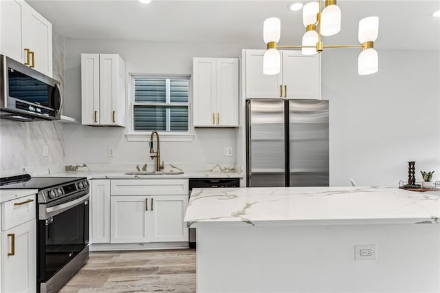 310507 Toulouse St, New Orleans, LA 70119 - kitchen with appliances with stainless steel finishes, light wood-style flooring, light stone counters, white cabinetry, and decorative light fixtures